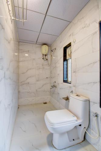 a white bathroom with a toilet and marble walls at Classic Residency in Pune