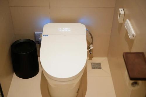 a white toilet in a bathroom with a trash can at Lu Ming Beiyuan Xi'an Zhongdu Drum Tower City Wall Store in Xi'an