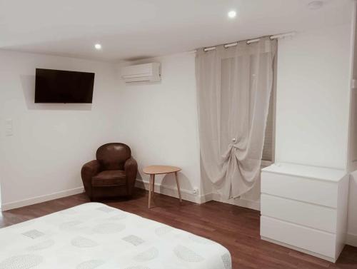 a bedroom with a bed and a chair and a television at appartement in Lussac-les-Châteaux