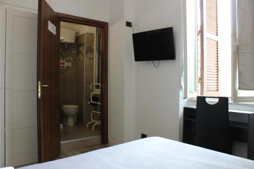 a room with a bathroom with a toilet and a television at Rooms Piramide in Rome