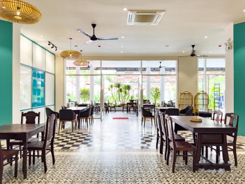 a dining room with tables and chairs and windows at Sujet Beach Hotel and Apartment Danang by Haviland in Da Nang