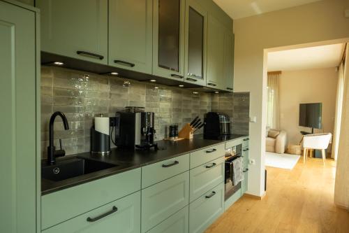 a kitchen with green cabinets and a sink at Wellnessen im Naturparadies nahe der südsteirischen Weinstraße - mit privater Panoramasauna & Whirlpool in Gamlitz