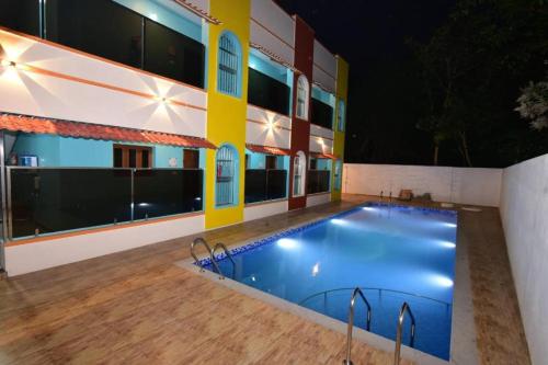 a swimming pool in front of a building at night at Thilo Guest House Auroville in Auroville