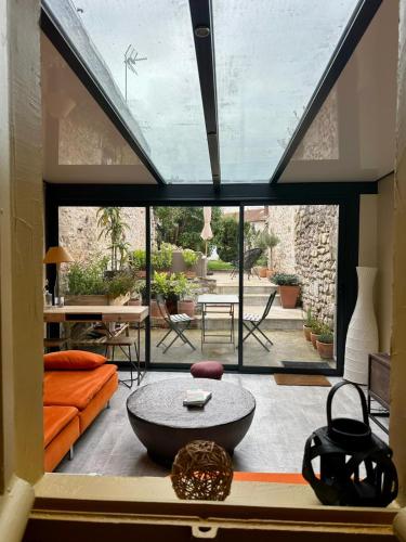 ein Wohnzimmer mit großem Fenster und Tisch in der Unterkunft Maison cosy pour 2 à Crépy, véranda et jardin in Crépy-en-Valois