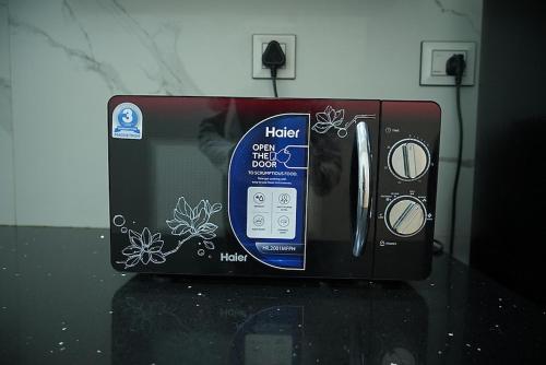 a black toaster oven with a bottle at Lime Tree Two BHK Service Apartment Golf Course Road Gurgaon in Gurgaon