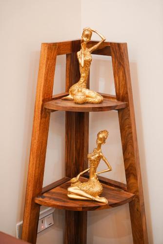 two gold statues of women on a wooden shelf at Lime Tree Two BHK Service Apartment Golf Course Road Gurgaon in Gurgaon