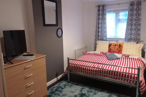 a bedroom with a bed and a dresser with a television at House - Sleeps 8 - Garden - Parking in Romford