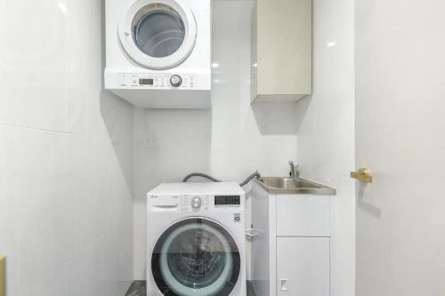 a washing machine in a bathroom with a sink at Sky-High Sanctuary Ocean Views - Pet Friendly in Gold Coast