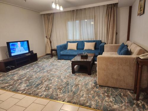 a living room with a couch and a tv at Sadeem Al Fajr Hotel Suites in Taif