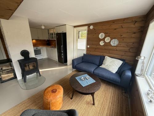 a living room with a blue couch and a stove at Cabin with Sauna and Aurora Views in Karlsøy