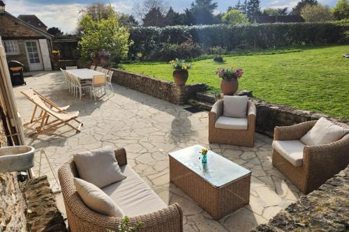 un patio con sedie in vimini e un tavolo in un cortile di L'Echappée d'Aristide - Giverny & 50 min Paris a Houlbec-Cocherel