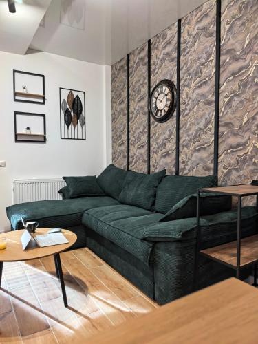 a living room with a green couch and a clock on a wall at Atractiv Two Luxury in Dudu