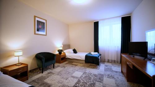 a hotel room with a bed and a desk and a television at Nova Hotel in Radom
