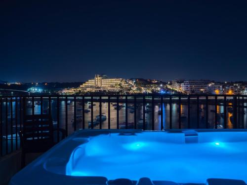 a bath tub sitting on top of a balcony at night at Sunny Beach House with Jacuzzi - Steps from the Sea in St Paul's Bay