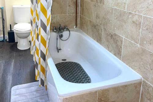 a bath tub in a bathroom with a toilet at House - Sleeps 10 - Garden - Parking in Romford