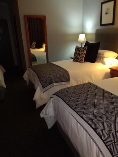 a hotel room with two beds and a mirror at Protea Hotel by Marriott Harrismith Montrose in Harrismith