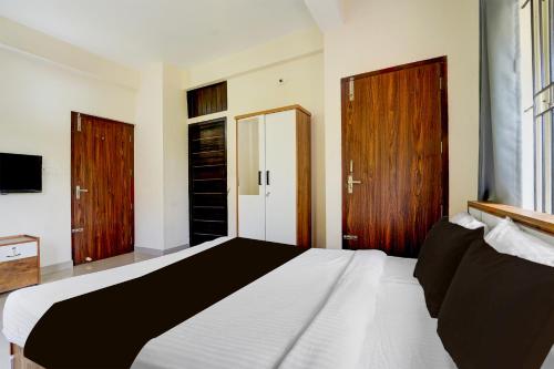 KakkayamにあるHotel O Calicut Near Calicut Medical Collegeのベッドルーム1室(白い大型ベッド1台、木製ドア付)
