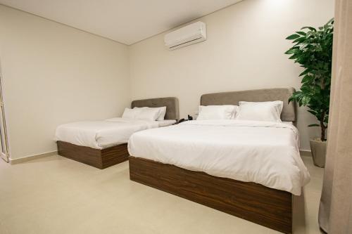 a bedroom with two beds with white sheets and a plant at Imperial Luxury Hotel in Cairo