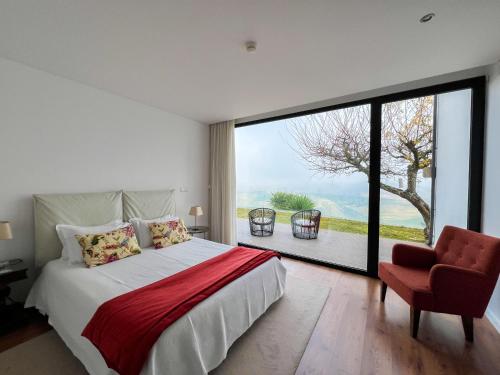 a bedroom with a bed and a chair and a large window at Spacious Villa with Private Pool & Garden in Douro, by Hopstays in Sabrosa