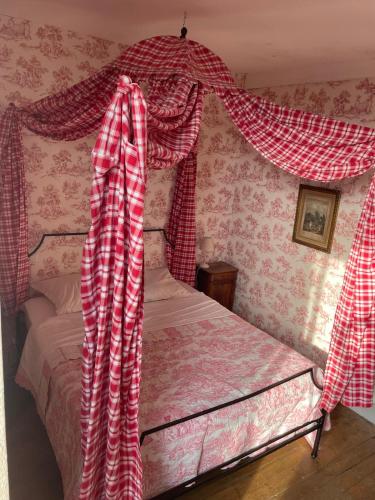 a bedroom with a bed with red and white curtains at Barabans Tower Cluny Abbay in Cluny