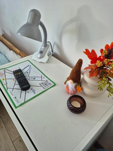 a table with a lamp and a remote control on it at Pokoje Bema 14 in Ciechocinek
