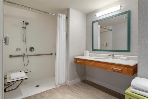 a bathroom with a sink and a shower with a mirror at Hampton Inn & Suites by Hilton Tampa Busch Gardens Area in Tampa