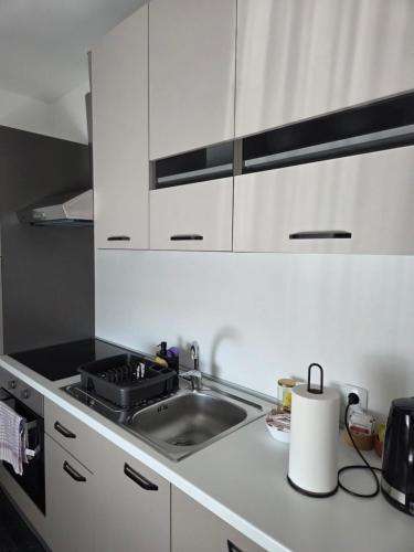 a white kitchen with a sink and a stove at Napoli sobe in Sveti Ivan Žabno
