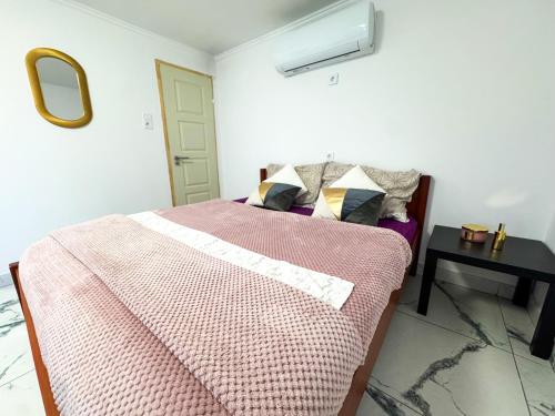 a bedroom with a bed with a pink blanket and a table at Rigókert Vendégház in Lakitelek