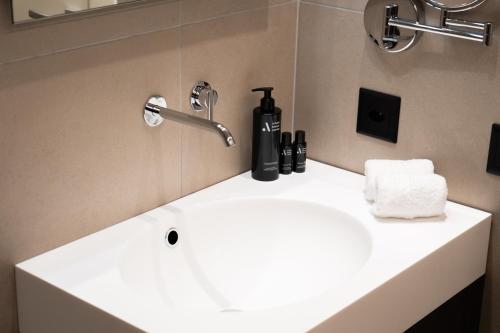 a bathroom sink with a black bottle of soap and towels at SELF CHECK IN Arbed Living Apartments Arbedo Castione in Arbedo-Castione