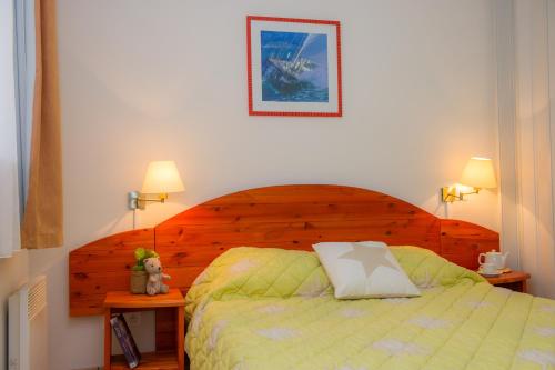 una camera da letto con un letto con testiera in legno di Résidence Goélia Le Cordouan a Soulac-sur-Mer