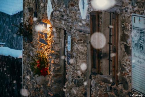 a stone wall with a cross and flowers on it at Il Granaio - Historic Molino Maufet Watermill - Lake Como in Colico