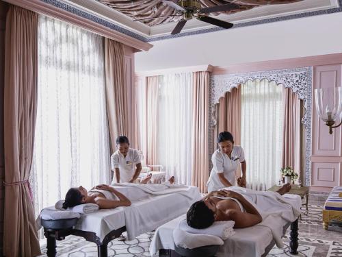 a couple of people laying in beds in a room at Raffles Udaipur in Udaipur