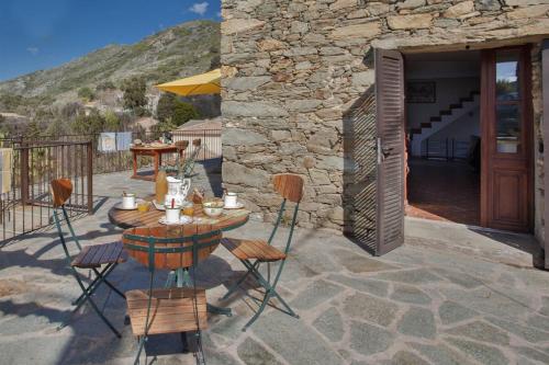 a patio with a table and chairs on a stone building at Casa Poggio in Barbaggio