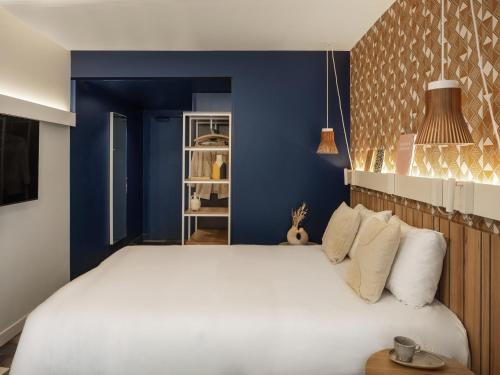 a bedroom with a large white bed and blue walls at Ibis Paris Gare Montparnasse Catalogne in Paris