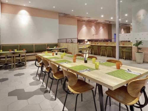 a dining room with a long table and chairs at ibis Styles Bogor Pajajaran in Bogor