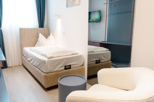 a bedroom with a bed and a chair and a mirror at Primus Hotel & Apartments in Vienna