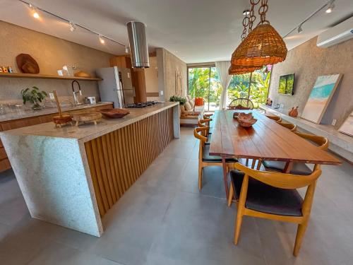 Una cocina y un comedor con mesa y sillas de madera. en Casa Nina Milagres, en São Miguel dos Milagres