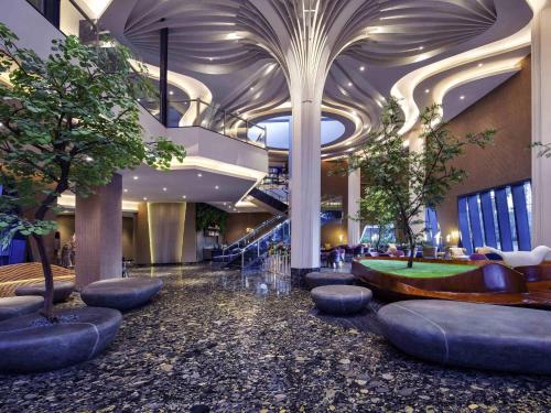 a lobby with trees and a staircase in a building at Grand Mercure Malang in Malang