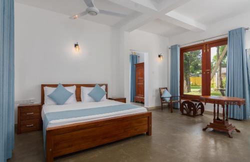 a bedroom with a bed and a desk and a window at Gedara Villa in Kalutara