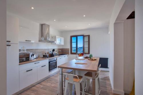 a kitchen with white cabinets and a wooden table at Casa Lisa - appartement dans le village de Monticello vue mer in Monticello