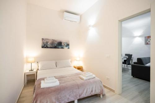 a white bedroom with a bed with two towels on it at Firenze Center - 5min to Duomo, Station - Wifi and AC in Florence