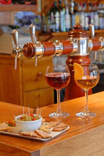 two glasses of wine and a plate of food on a counter at Logis Hôtel restaurant La Remise in Le Bleymard