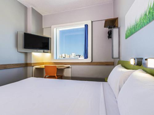 a bedroom with a bed and a tv and a desk at Ibis Budget Fortaleza Praia de Iracema in Fortaleza