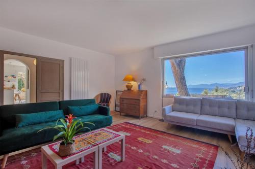 a living room with a green couch and a large window at Casa Marinu Muntese in Erbalunga