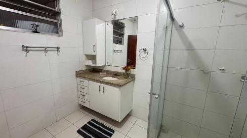 a white bathroom with a sink and a shower at Hostel Arraial in Arraial do Cabo