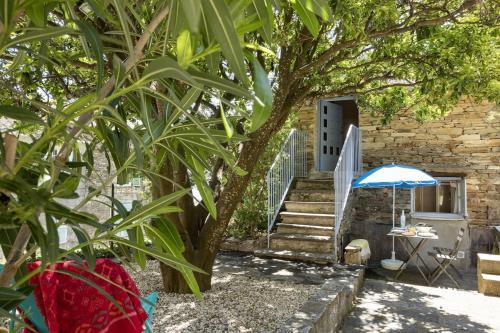 Una casa de piedra con una escalera y una sombrilla azul. en La Bergerie, en Brando