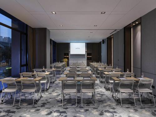 a conference room with tables and chairs and a screen at Novotel Tianjin Drum Tower in Tianjin