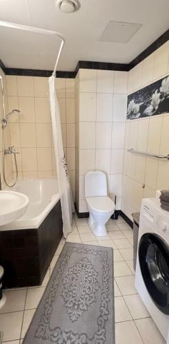 a bathroom with a tub and a toilet and a washing machine at Luxury Nightlights NELLI Apartment in Tallinn
