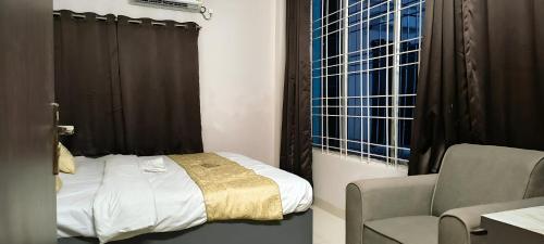 a bedroom with a bed and a chair and a window at Hotel Silver Fountain Ranchi in Rānchī