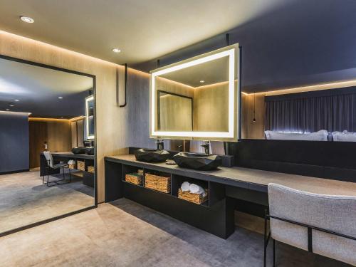 a hotel room with a bed and a vanity with a mirror at Novotel Lencois Paulista in Lençóis Paulista